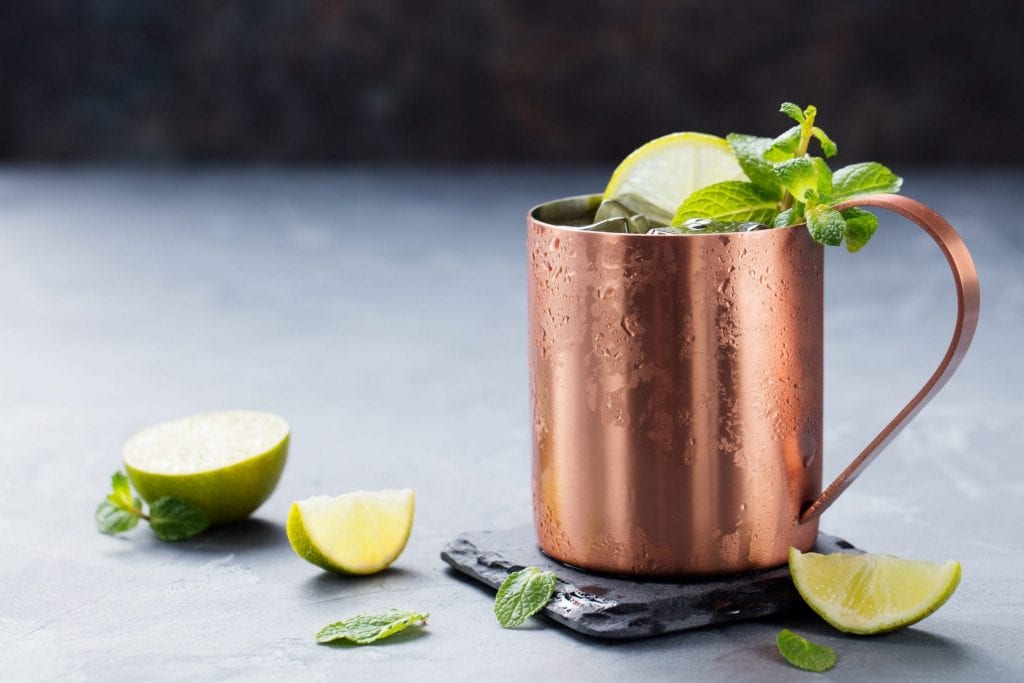 Cold Moscow Mules cocktail with ginger beer, vodka, lime Grey stone background. 