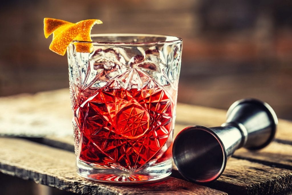 Cocktail Negroni on a old wooden board. Drink with gin, campari martini rosso and orange