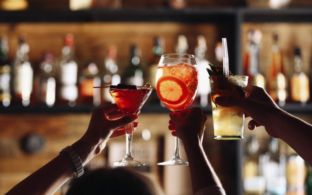 Group of people saying cheers over a cocktail in a bar