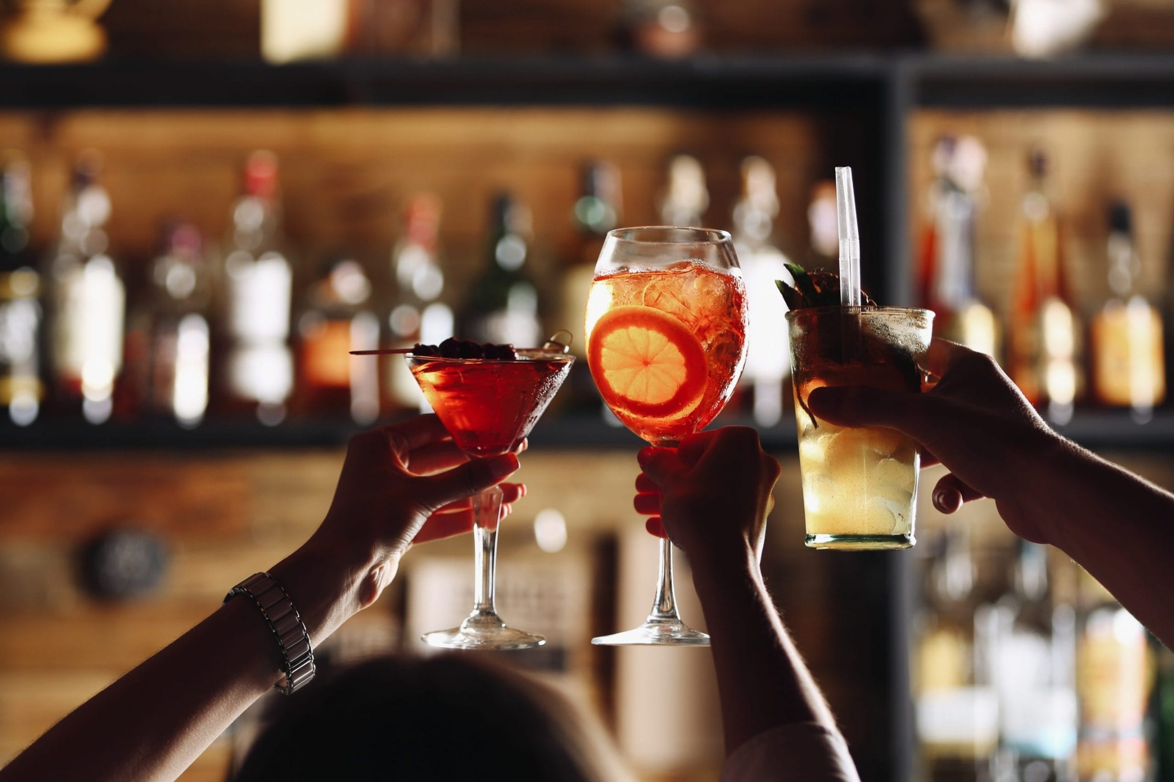 Spirit of Wales Distillery - Ways to celebrate world cocktail day Group of people saying cheers over a cocktail in a bar