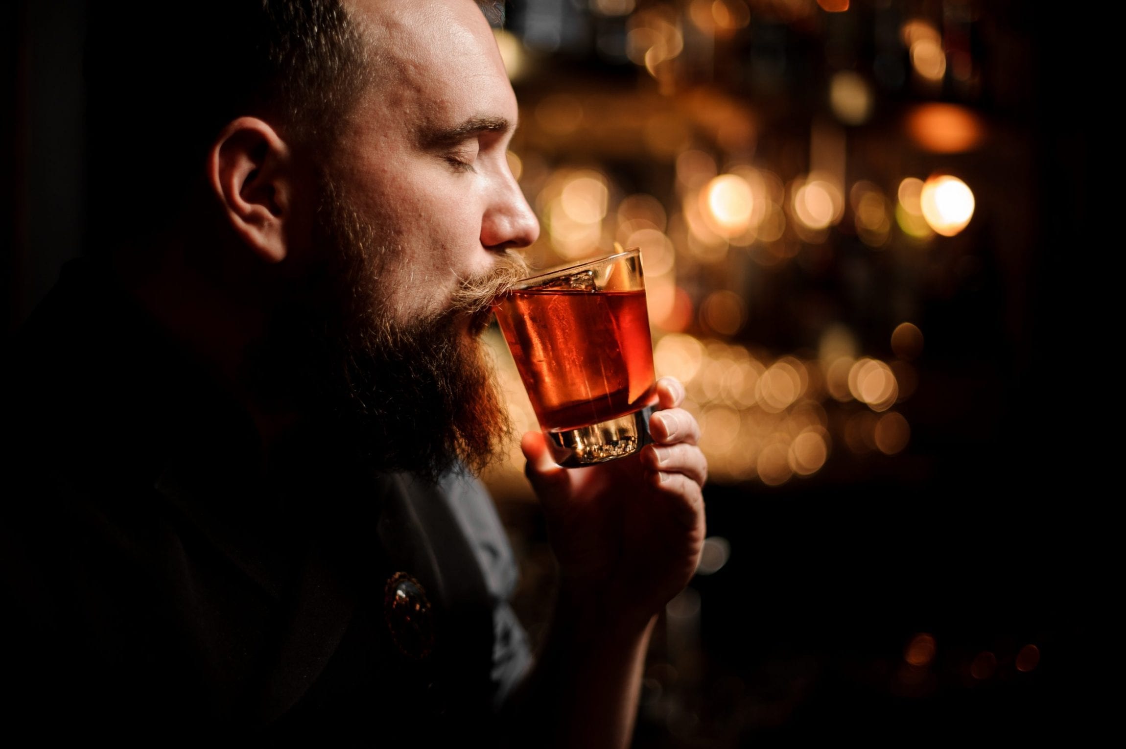 Bartender tasting a cocktail in the glass with a orange zest as a decor